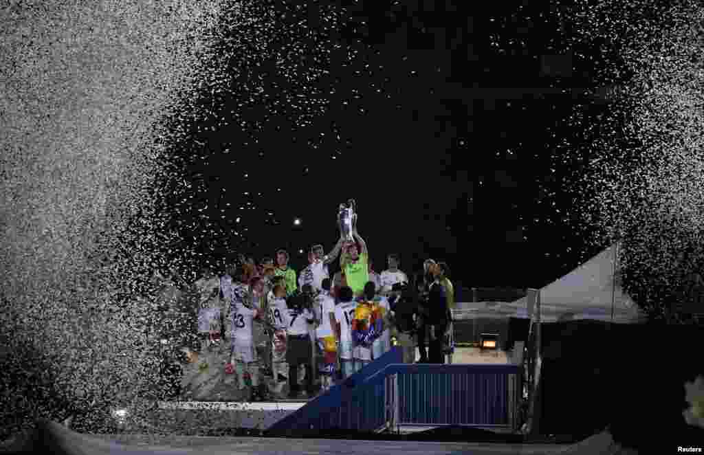 Real Madrid&#39;s Iker Casillas (R) and Sergio Ramos hold up the Champions League trophy during a victory ceremony at Santiago Bernabeu stadium in Madrid, May 25, 2014. Real Madrid won its 10th Champions League title after beating Atletico Madrid in the final match in Lisbon.