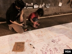 有家長帶同小朋友參與佔領中環金鐘的集會，在一張白紙上寫上心聲。（美國之音湯惠芸攝）