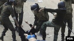 Pasukan keamanan Mesir melakukan kekerasan terhadap seorang demonstran perempuan di Kairo (23/12). Penguasa militer Mesir mencurigai keterlibatan asing dalam menyulut kerusuhan politik di Mesir.