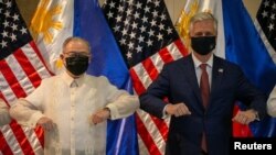 رابرت اوبراین، مشاور امنیت ملی کاخ سفید، و وزیر خارجه فیلیپین در مراسمی در مانیل آرنج‌هایشان را به یکدیگر می‌زنند.