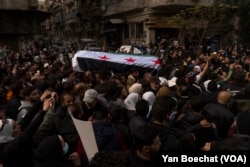 The body of activist Mazen al-Hamada is taken in a procession around downtown Damascus, Syria, before his funeral, Dec. 13, 2024.