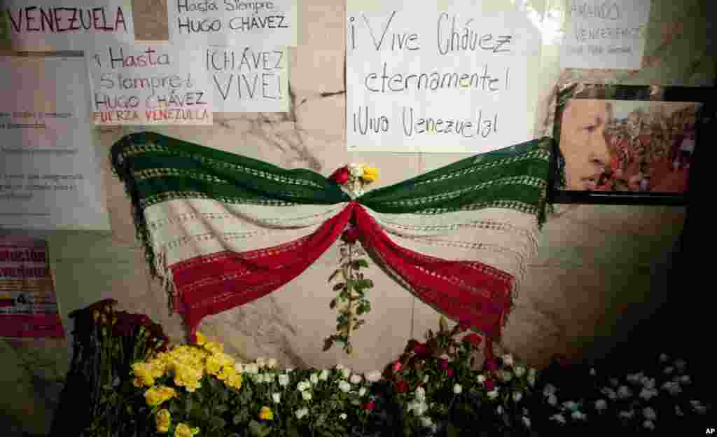 A mourning ribbon with the colors of the Mexican flag sits next to an image of Venezuela&#39;s President Hugo Chavez in front of Venezuela&#39;s embassy in Mexico City, March 5, 2013. 