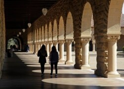 FILE - Students walk on the Stanford University campus, March 14, 2019, in Santa Clara, Calif.