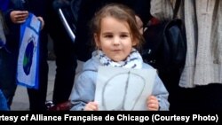 A girl holds a ‘Peace for Paris’ symbol, created by graphic designer Jean Jullien, at a vigil outside the French consulate in Chicago, Ill., Nov. 15, 2015.. 