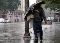 A man walks through rain in the French Quarter caused by Hurricane Barry in New Orleans, July 13, 2019.