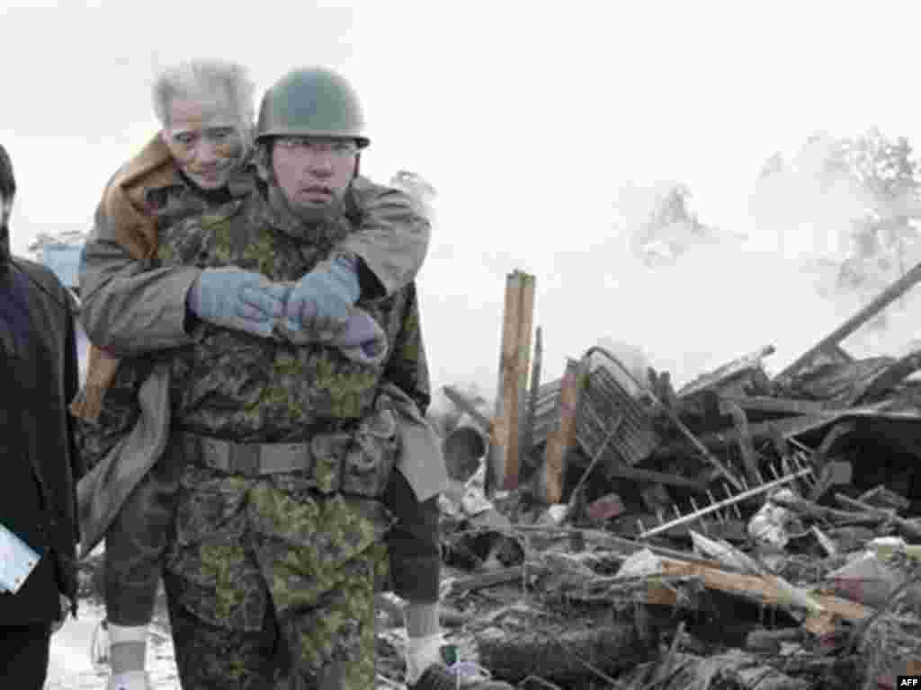 An elderly man is being carried by Self-Defense Force member in the tsunami-torn Natori city, Miyagi Prefecture, northern Japan, Saturday morning, March 12, 2011, one day after strong earthquakes hit the area.