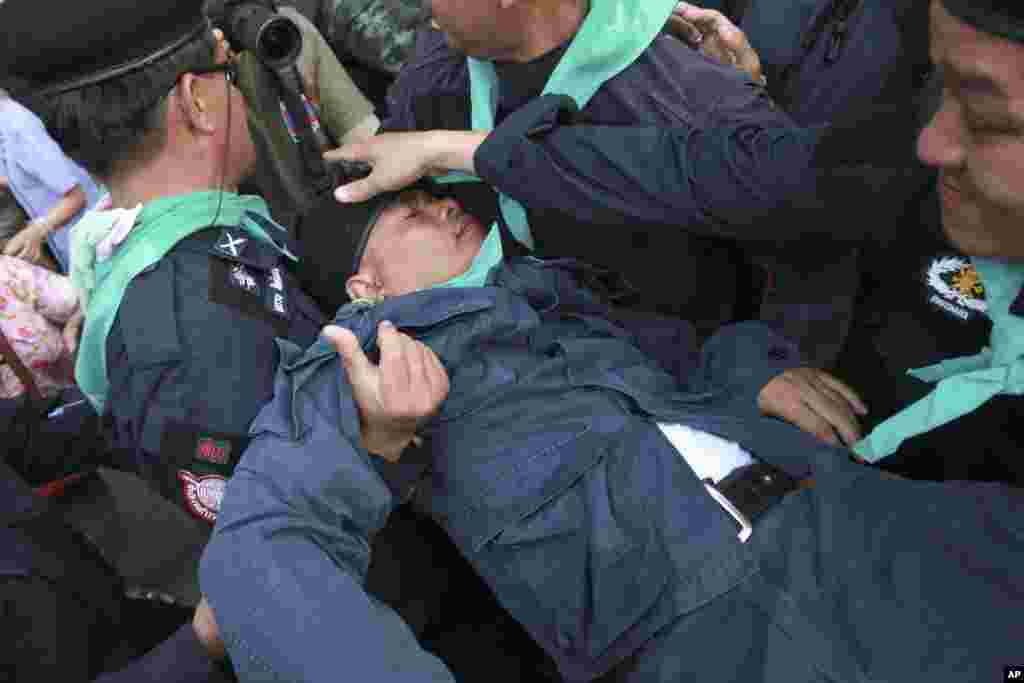 A Thai riot police officer (center), is carried by colleagues after he was knocked down by an object thrown by protesters during an anti-coup demonstration at the Victory Monument, in Bangkok, May 28, 2014.