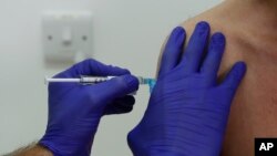 In this Wednesday, Oct. 7, 2020, file photo, a Phase 3 Novavax coronavirus vaccine trial volunteer is given an injection at St George's University hospital in London. (AP Photo/Alastair Grant, File)