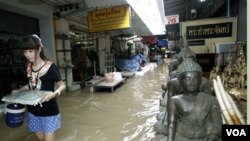 Seorang remaja berjalan di sebuah gang di tengah banjir parah di Thailand.