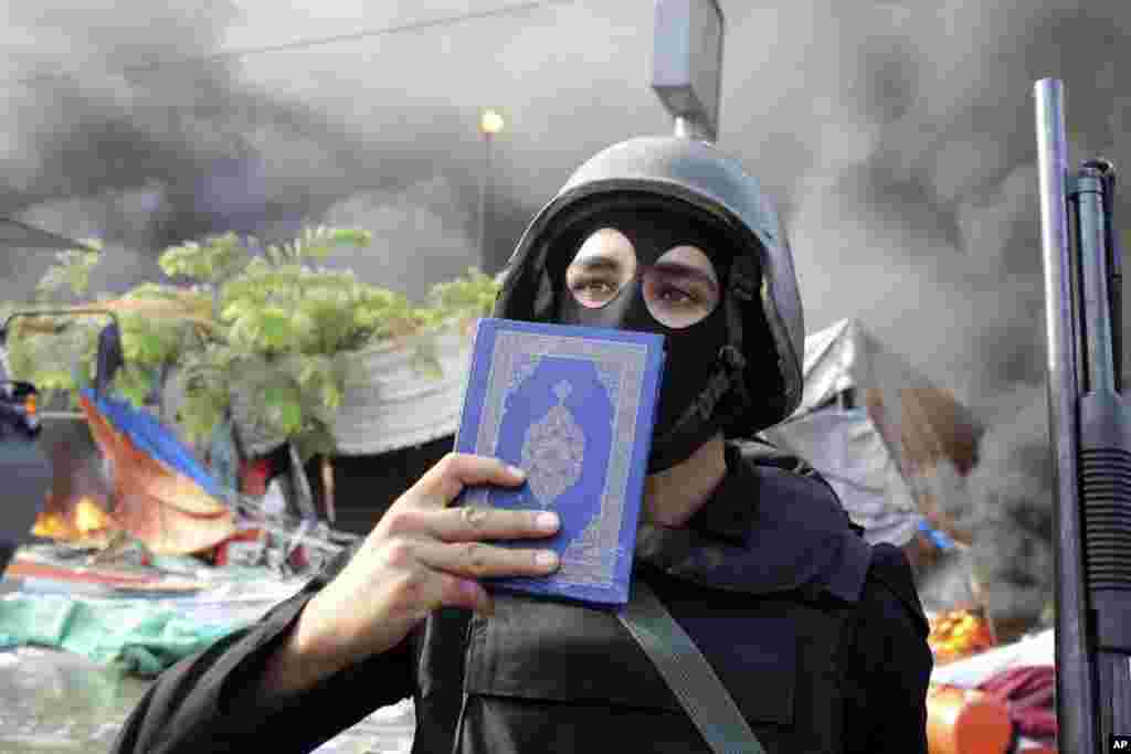A member of the Egyptian security forces holds up a copy of the Quran as clear they clear the smaller of the two sit-ins by supporters of ousted Islamist President Mohammed Morsi, near the Cairo University campus in Giza, Cairo, Egypt, Wednesday, Aug. 14,