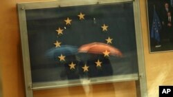 Passers-by are reflected in an artwork based on the European Union flag, with one star missing, in the European Commissions headquarters in Brussels, Nov. 12, 2018. 