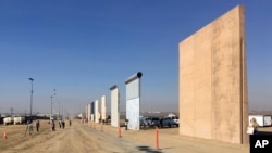 FILE - People look at prototypes of a border wall, Oct. 26, 2017, in San Diego. Contractors have completed eight prototypes of President Donald Trump's proposed border wall with Mexico, triggering a period of rigorous testing to determine if they can repel sledgehammers, torches, pickaxes and battery-operated tools. 