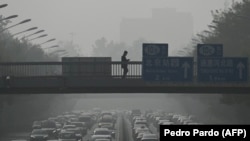 Para pejalan kaki melintas di jembatan penyeberangan saat lalu lintas padat di tengah kabut polusi udara di Beijing, China, 1 November 2023. (Foto: Pedro Pardo/AFP)