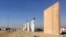 FILE - People look at prototypes of a border wall, Oct. 26, 2017, in San Diego. Contractors have completed eight prototypes of President Donald Trump's proposed border wall with Mexico, triggering a period of rigorous testing to determine if they can repel sledgehammers, torches, pickaxes and battery-operated tools. 