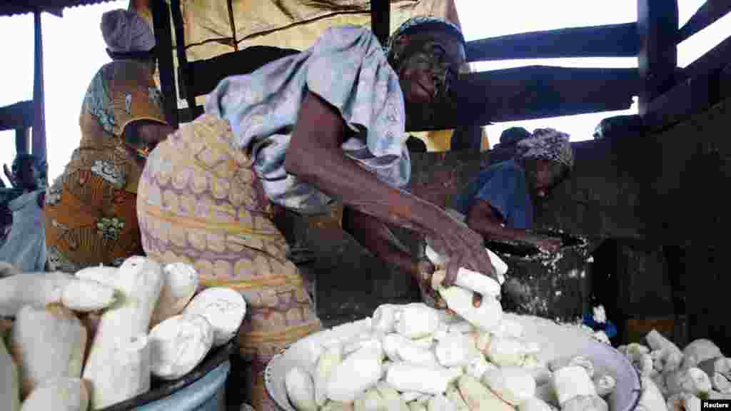 Women work in a cassava grinding mill.