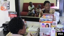 A customer waits for her hair stylist in Rita Dantaa's hair salon in downtown Johannesburg, May 16, 2014 (Gillian Parker for VOA).