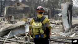 A firefighter surveys a wildfire-damaged neighborhood, Sunday, July 29, 2018, in Keswick, Calif.