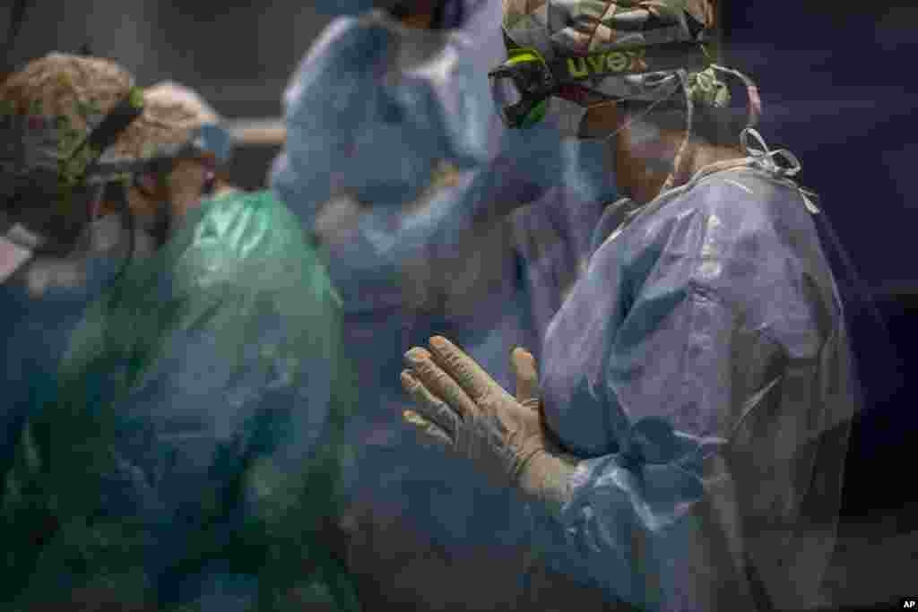 A doctor pauses as others perform a tracheotomy on a COVID-19 patient in critical care in Barcelona&#39;s Hospital del Mar the Intensive Care Unit, Spain, Thursday, Nov. 5, 2020. Some hospitals in Spain say they are only now beginning to feel some relief foll