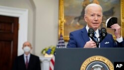 President Joe Biden removes his face mask as he prepares to deliver remarks on the retirement of Supreme Court Associate Justice Stephen Breyer, left, in the Roosevelt Room of the White House in Washington, Jan. 27, 2022. 