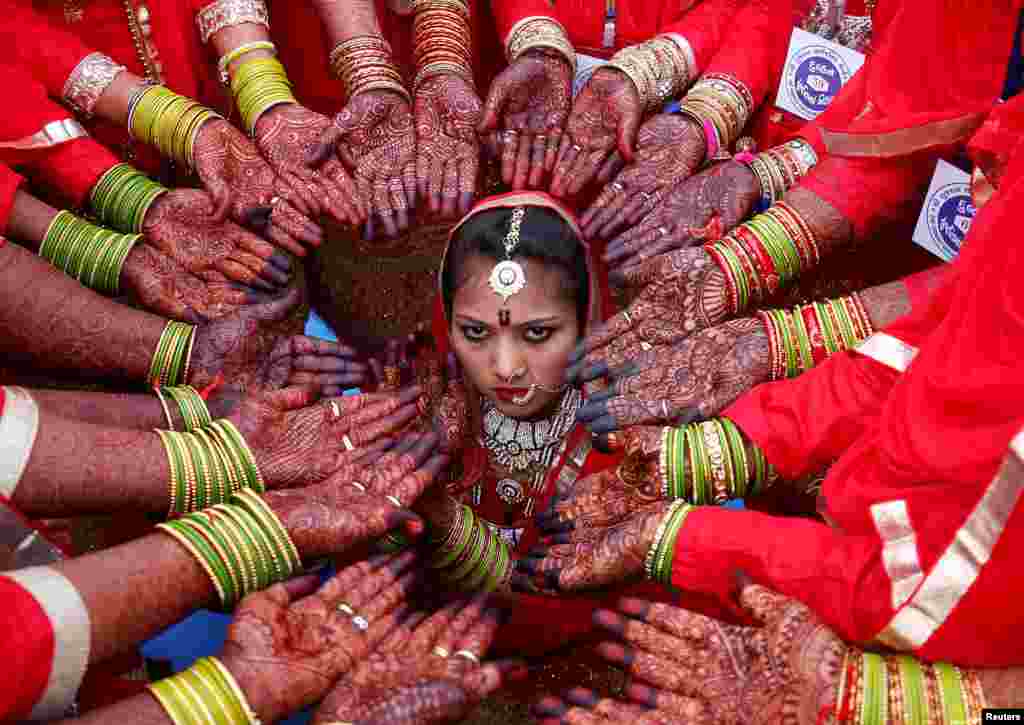 인도 아흐메다바드에서 열린 합동결혼식에서 적갈색 염료로 손을 장식한 신부들이 한 명의 신부 주변을 둘러싸고 있다. 결혼식 주최측는 70명의 이슬람교 부부들이 이번 합동결혼식에 참여했다고 밝혔다.