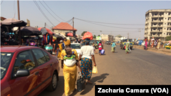 Des femmes quittant un marché de la banlieue de Conakry avec des sacs plastiques, en Guinée, le 17 janvier 2018. (VOA/Zacharia Camara)