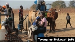 A woman plays with her baby at a water point on the outskirts of the capital Harare on November 14, 2021. (AP Photo/Tsvangirayi Mukwazhi)