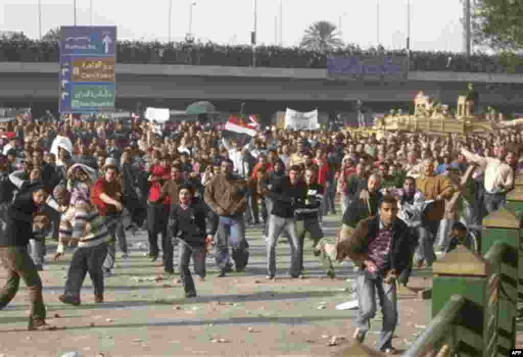 Supporters of President Hosni Mubarak run towards anti-Mubarak protesters in central Cairo, Egypt, Wednesday, Feb.2, 2011. Several thousand supporters of President Hosni Mubarak, including some riding horses and camels and wielding whips, clashed with ant