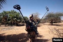 A French soldier carries mine detection equipment to search for mines outside Gao, Mali, March 9 2013.
