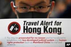 Seorang pemrotes memegang spanduk peringatan tentang bahaya bepergian ke Hong Kong di bandara di Hong Kong, Jumat, 9 Agustus 2019.
