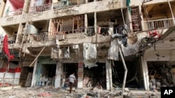 A man inspects the site of a car bomb attack in Baghdad, June 8, 2014. 