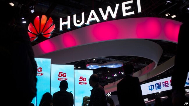 2019年10月31日,在北京的PT博览会上,与会者走过中国科技公司华为的5G服务展示台(美联社)。