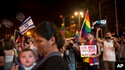 FILE - Israelis wave flags and hold signs during a rally demanding equal rights for members of the country's the LGBT community, in Tel Aviv, Israel, July 22, 2018. 