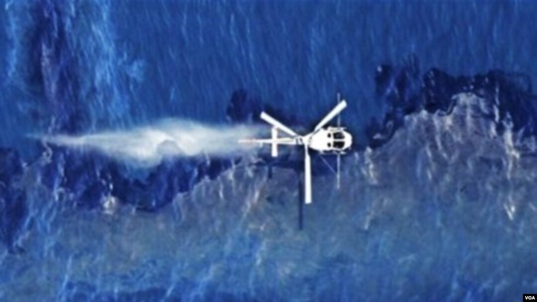 Helikopter menyempotkan dispersan di atas tumpahan minyak kapal kargo Rena yang terjebak di terumbu karang Tauranga, Selandia Baru (foto:dok).