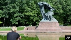 A tourist sits by the Chopin monument in Lazienki park in Warsaw, Poland, Sept. 3, 2018.