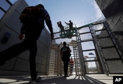 The marines install an accordion wire, above, while pedestrians leave the United States for Mexico at San Ysidro's entry port on November 16, 2018 in San Diego.