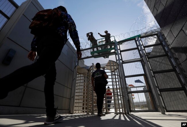 Marines install concertina wire, above, as pedestrians leave the United States for Mexico at the San Ysidro port of entry, Nov. 16, 2018, in San Diego.