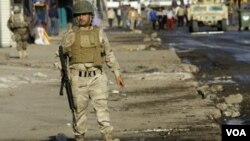 Иракский солдат охраняет место взрыва на багдадском рынке