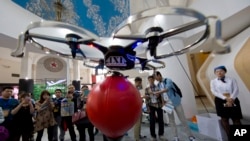 在北京举行的中国国际模型博展会上，参观者观看由手机操纵的无人机。（2015年4月24日）