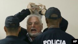 El expresidente de Panamá Ricardo Martinelli responde a los periodistas mientras levanta las manos esposadas y es escoltado por la policía a una audiencia en la Corte Suprema, el 19 de noviembre de 2018, en Panamá. 