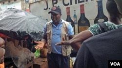 Red Cross worker Joseph Garber talks to people in the east part of Freetown about Ebola prevention. July 28, 2015 (N. deVries/VOA)