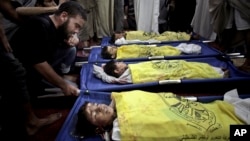 FILE - Palestinians mourn over the lifeless bodies of four boys from the same extended Bakr family, covered with yellow flags of Fatah movement, in the mosque during their funeral in Gaza City in July.