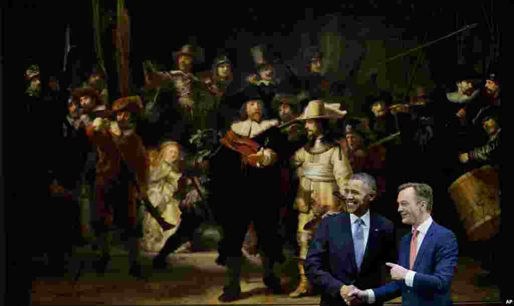 U.S. President Barack Obama and museum director Wim Pijbes pose in front of Dutch master Rembrandt's The Night Watch painting during a visit to the Rijksmuseum in Amsterdam, March 24, 2014. 