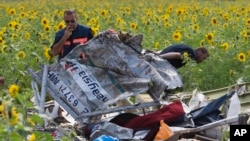 Dutch investigators examine pieces of the crashed Malaysia Airlines Flight 17 in the village of Rassipne, Donetsk region, eastern Ukraine, July 25, 2014. 