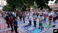 Worshippers wearing masks to help stop the spread of the coronavirus, offer Eid al-Adha prayer while maintaining a social distance in front of the Gazi Husrev-beg mosque in Sarajevo, Bosnia, Friday, July 31, 