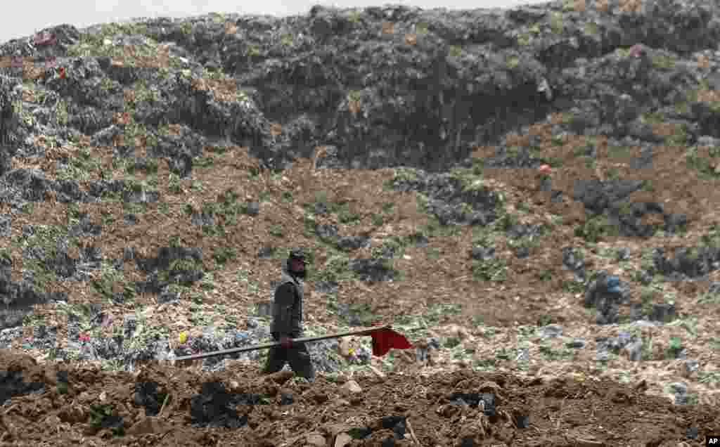 A Sri Lankan army soldier walks to erect red flags to demarcate danger zones following the collapse of a garbage mound in Meetotamulla, on the outskirts of Colombo.