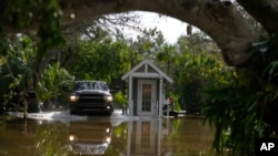 Una camioneta pasa junto a una puerta de guardia en una calle inundada en Siesta Key, Florida, luego del paso del huracán Milton, el 10 de octubre de 2024.