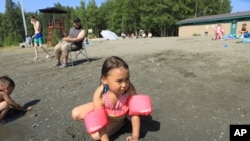 Milana Acuna, 5, makes a mud creation while at Goose Lake as her father, Manny Acuna, looks on, July 5, 2019, in Anchorage, Alaska.