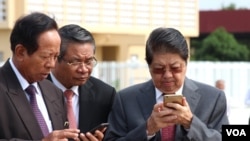 Senior Cambodian government officers are using their smart phones while awaiting the return of Cambodian Prime Minister Hun Sen from France at Phnom Penh International Airport, October 28, 2015.