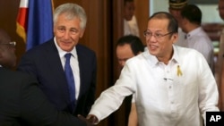 Philippine President Benigno Aquino III, right, shakes hands beside U.S. Defense Secretary Chuck Hagel, center, during his visit at the Malacanang Presidential Palace in Manila, Philippines, Aug. 30, 2013.