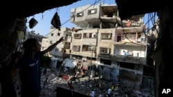 Warga Palestina memeriksa reruntuhan gedung pasca serangan misil Israel atas kota Gaza (10/7).